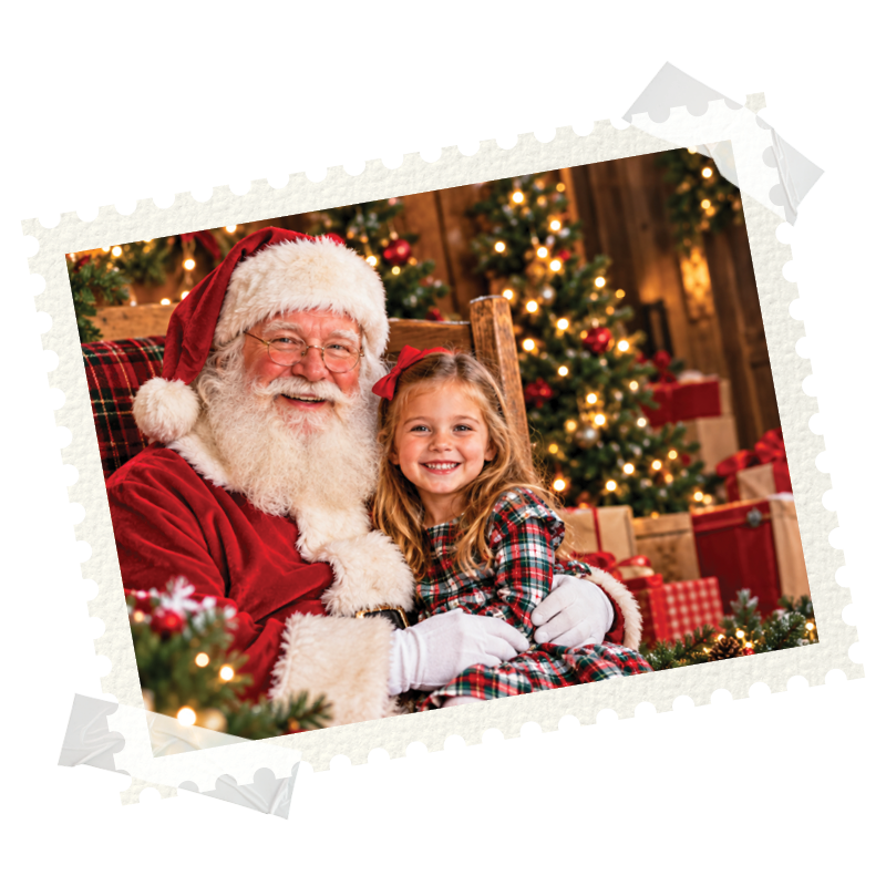 Santa smiling with a young girl in front of a Christmas tree